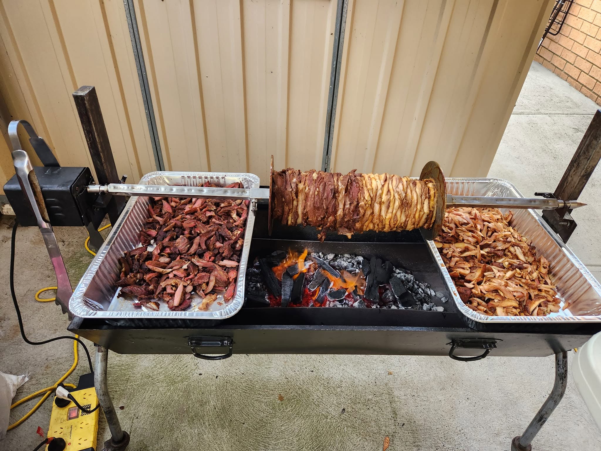 Lamb and chicken gyros cooking over charcoal