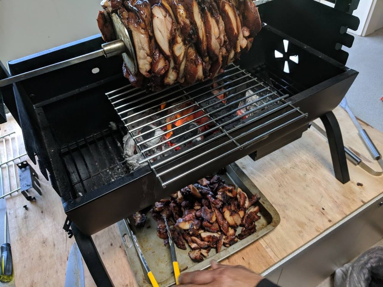 Compact charcoal spit roaster cooking meat